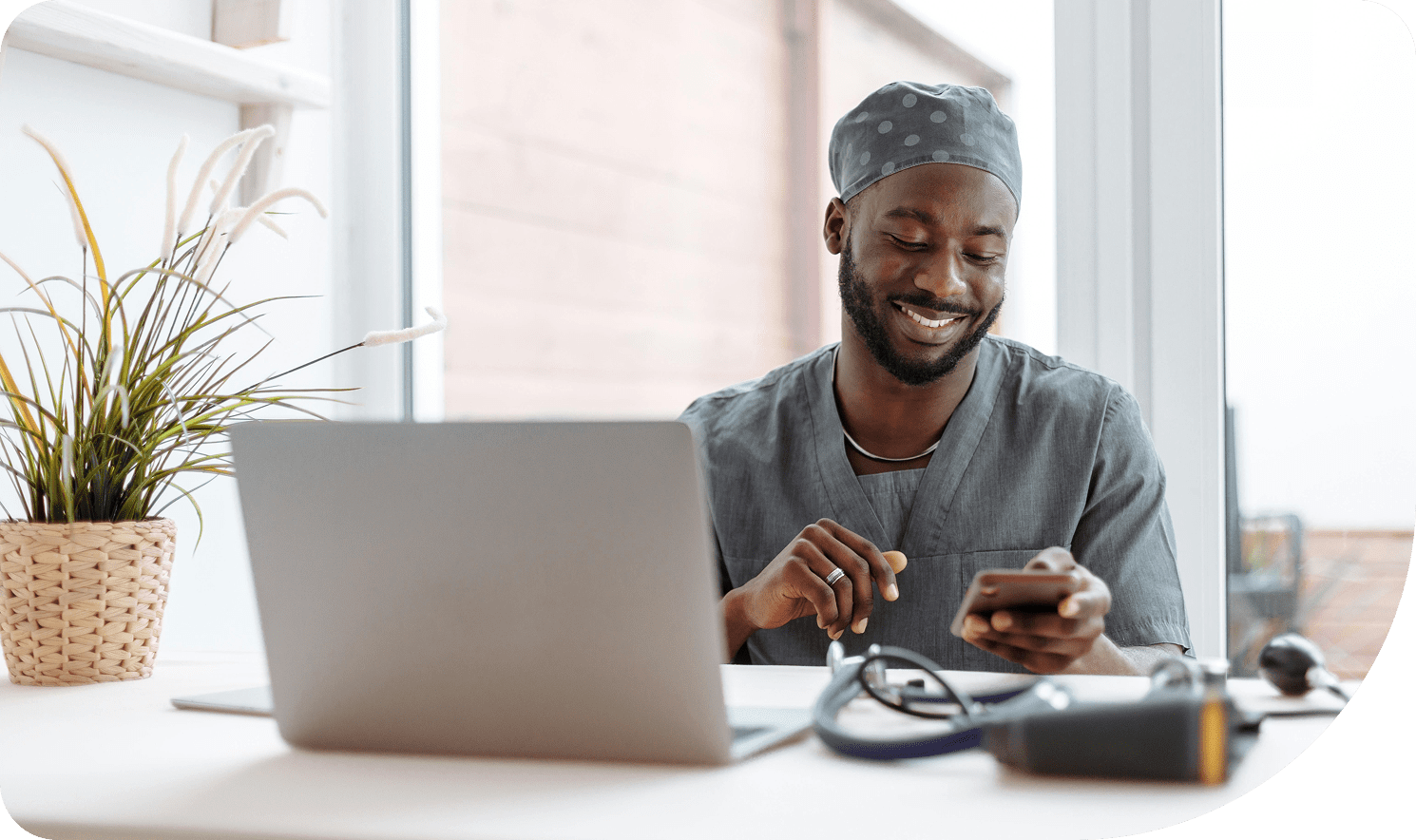 Man smiling while using smartphone at desk.