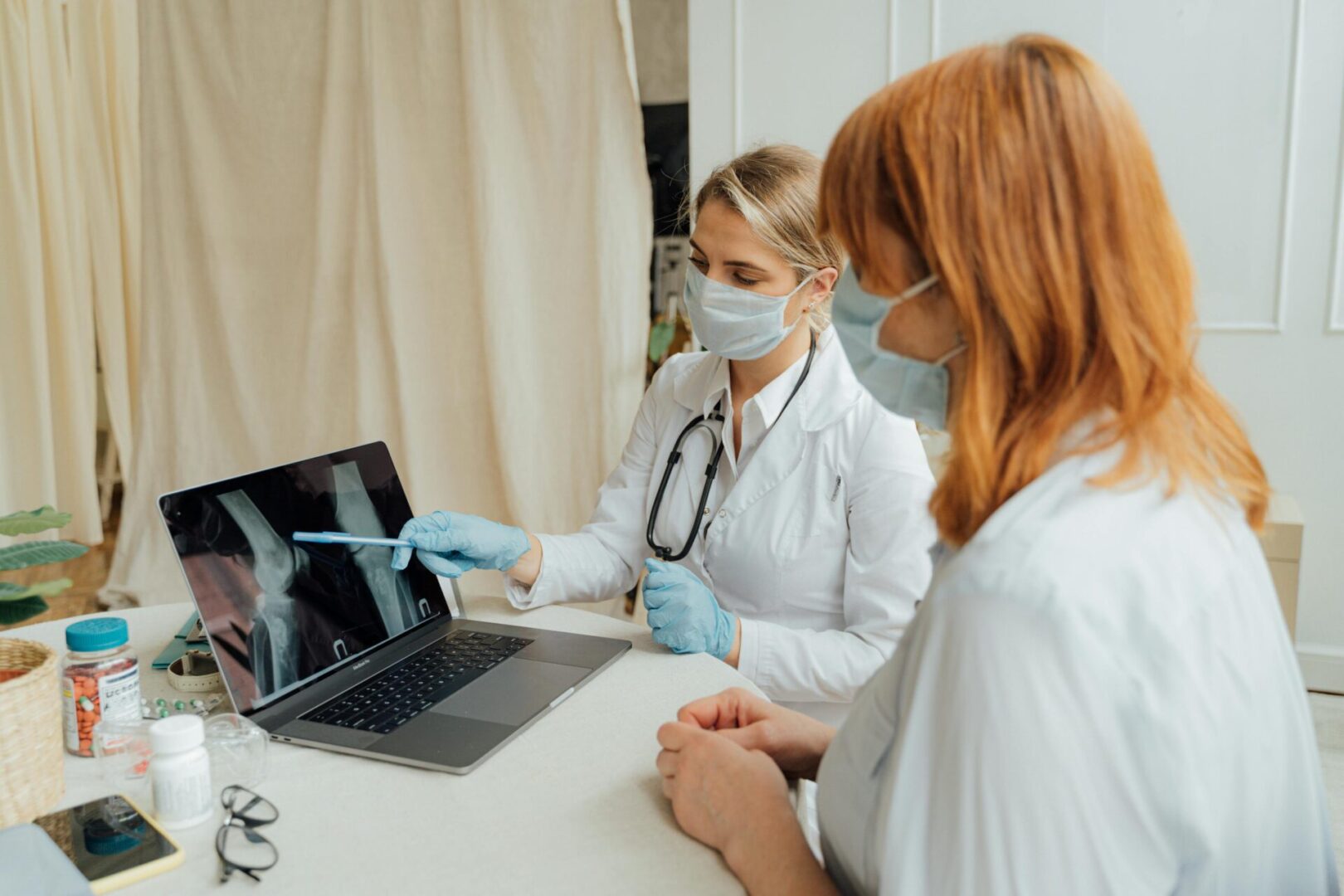 Doctors discussing X-ray on laptop screen.