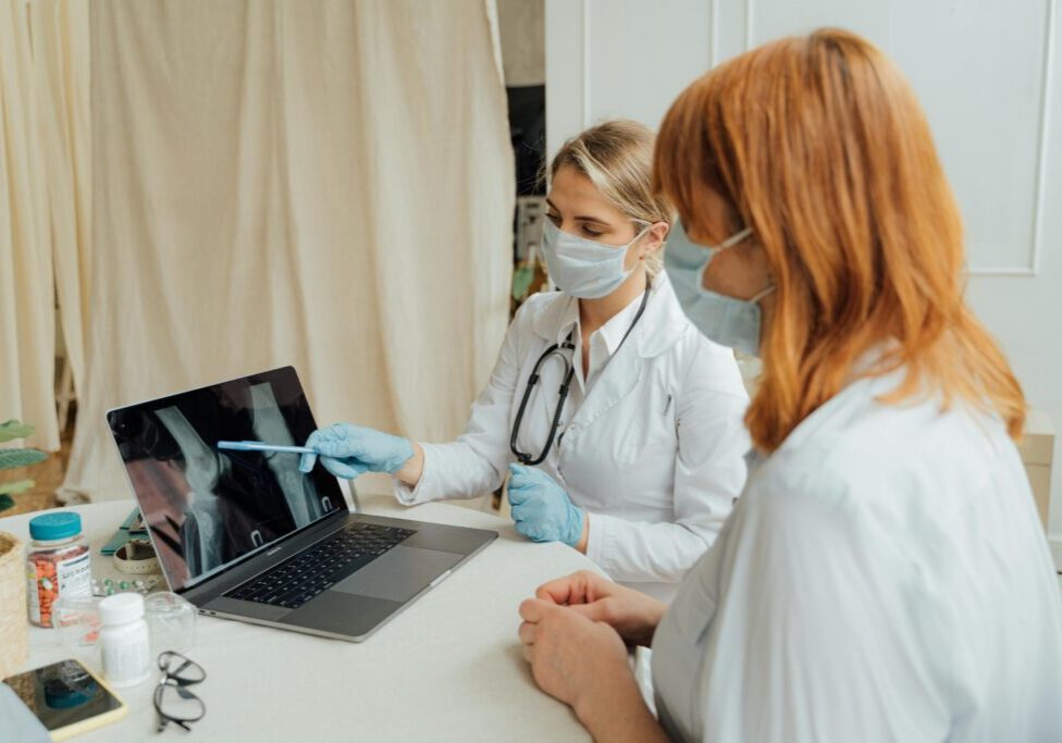 Doctors discussing X-ray on laptop screen.